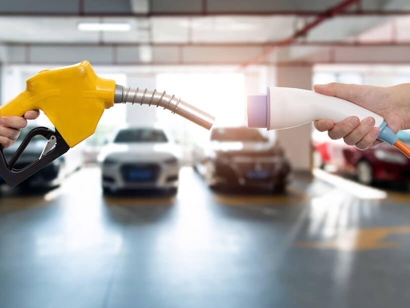 The yellow nozzle on the left represents conventional fuel, such as diesel or gasoline. The white plug on the right represents the charging connector for an electric vehicle.