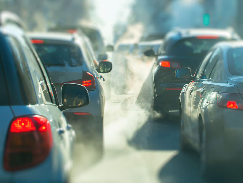 Cars in traffic surrounded by pollution from the exhaust